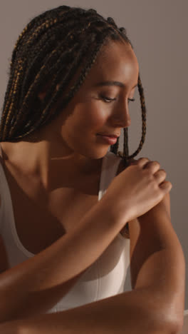 Studio-Skincare-Beauty-Shot-Of-Young-Woman-With-Long-Braided-Hair-Putting-Moisturiser-Onto-Arms